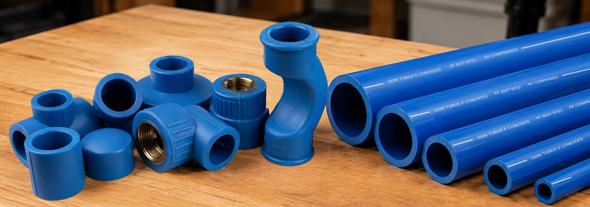 Tubos e conexões PPR AZUL Odin sobre bancada, com fábrica ao fundo, específicos para redes de ar comprimido